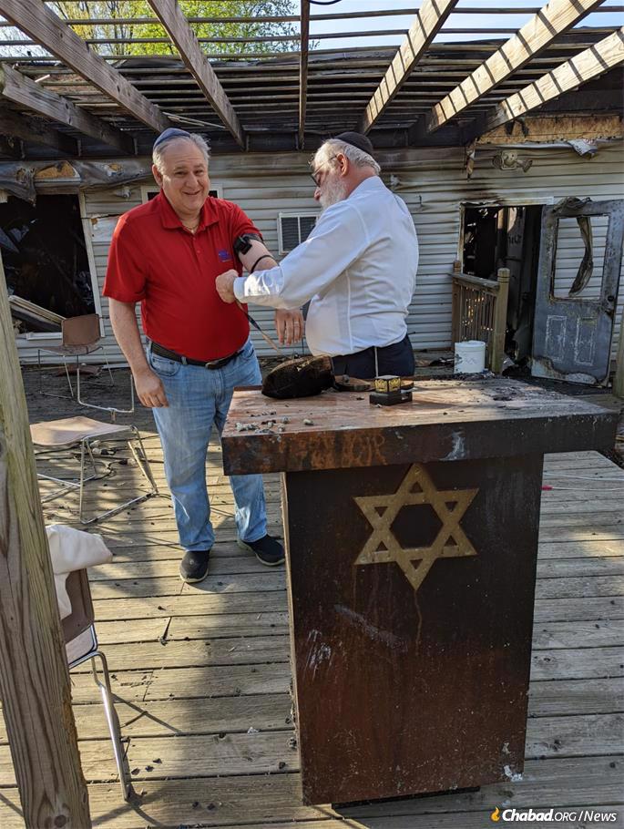 Community members came by the day after the fire to help with the cleanup and were given the opportunity to don tefillin.