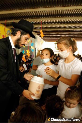 Rabbi Yossef Levy helps schoolchildren do a mitzvah in Rosario, Argentina.