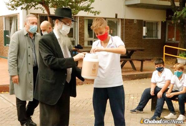 Rabbi Shlomo Tawil helps a student give charity.