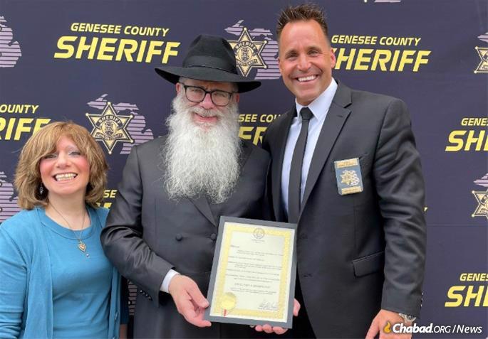 Shanie Weingarten and Rabbi Yisrael Weingarten receive the “Education and Sharing Day“ proclamation from Sheriff Chris Swanson.