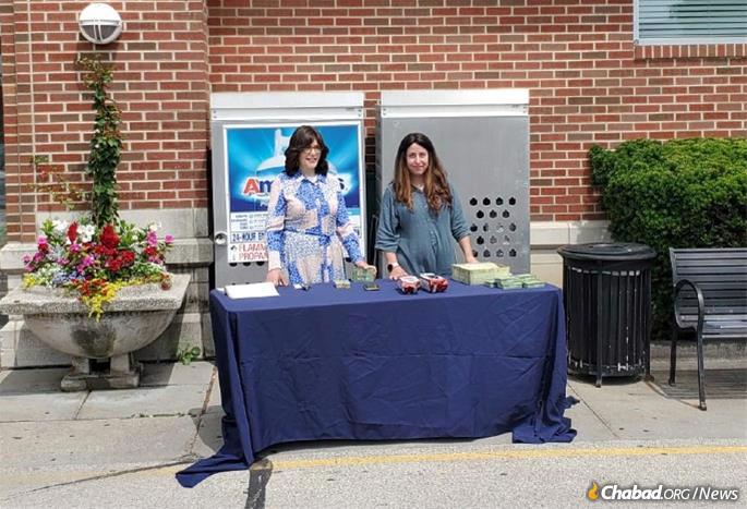 From left: Libby Wolff and Rochel Telsner give out Shabbat candle kits