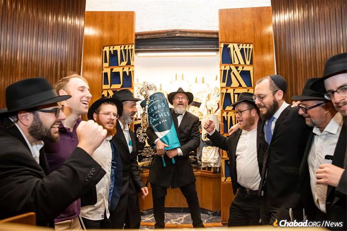 Rabbi and congregants escort the new Torah to its home in the ark at Chabad of the Beaches.