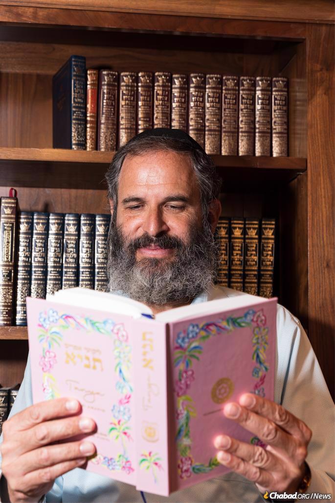 Rabbi Moshe Scheiner looks inside the newly printed and bound Tanya