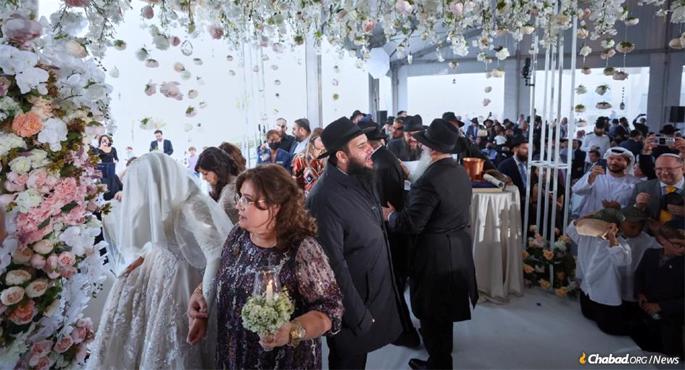 Lea Hadad, escorted by her mother and mother-in-law, encircles Rabbi Levi Duchman under the chuppah (canopy). (Credit: Jewish UAE / Christopher Pike)