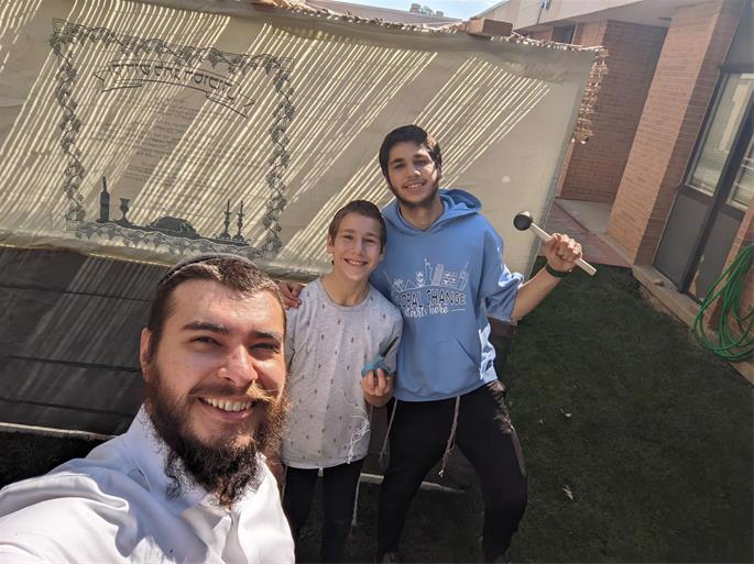 Rabbi Tzvi Tornek assembles a sukkah at a Naperville high school ahead of the holiday, with volunteers Eli and Yisroel Goldstein.