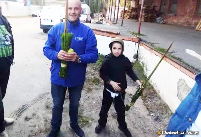 Nine-year-old Yoel Dovid Lenau, right, helps a Jewish man shake the lulav and etrog this past Sukkot in Kiev.