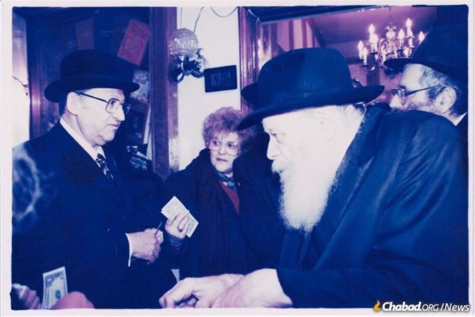Cantor Wilhelm Silber receives a dollar and blessing from the Rebbe, while his late wife, Judy, looks on.