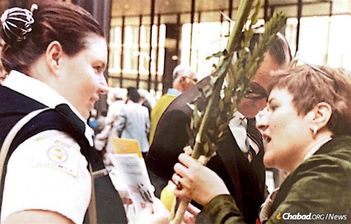 Judy Silber (right) helps a passer-by make a blessing over the Four Kinds outside the Chabad-sponsored public sukkah outside the Chicago City Hall.
