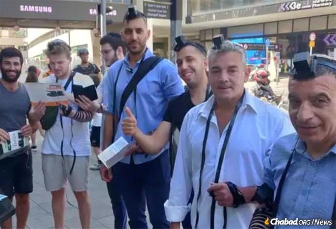 Men line up outside the Dizengoff Mall in the center of Tel Aviv to put on tefillin after learning about attacks on the Chabad program.