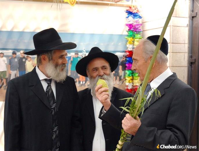 Chabad activists in Israel assist then-President Shimon Peres make the blessing on the lulav and etrog in 2007. - Photo: Moshe Milner/GPO.