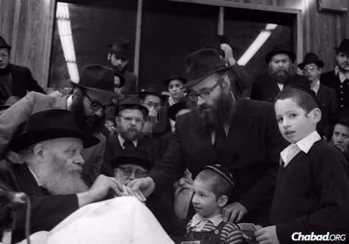 Rabbi Shmuel “Moul&#233;” Azimov receives a dollar and a blessing from the Rebbe.