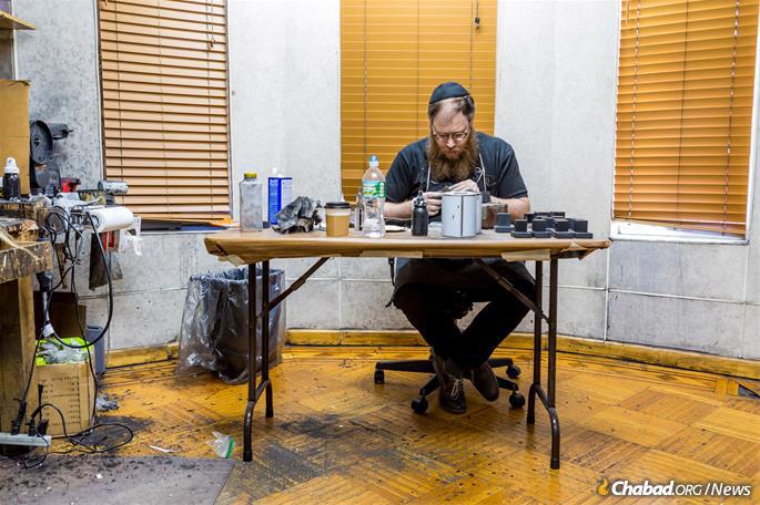 Aside from the intricate scribal work, much goes into making a pair of tefillin, with the black leather boxes being made by hand as well. - Photo: Eliyahu Papyra/Chabad.org.
