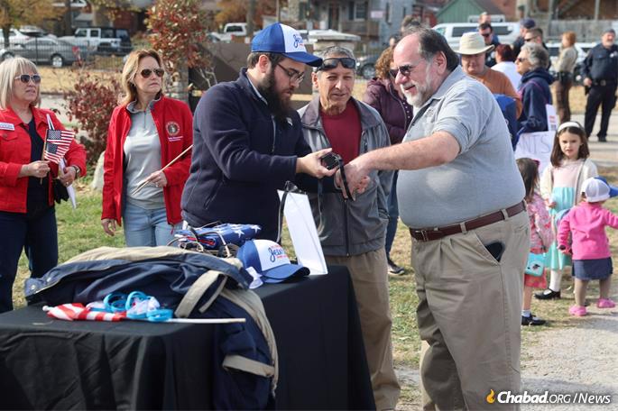 Rabbi Chaim Landa helps a participant attending a rally in St. Charles, Mo., show his support both for Israel and the hostages being held in the Gaza Strip by putting on tefillin. - Photo by Bill Motchan