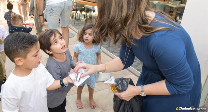 A child from a displaced Israeli community receives a kiddush cup from Chani Klein, co-director of Chabad of Eilat.