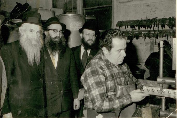 Within two days of the Rebbe&#39;s call to share the message and light of Chanukah, the Lubavitch Youth Organization in New York had found metal-stamping shop to fulfill an initial order of 10,000 tin menorahs. Pictured, from left: Rabbi Shmuel Dovid Raichik, Rabbi Dovid Raskin and Rabbi Shmuel Butman, both of LYO, observe as a worker creates a tin-menorah mold. - Photo: Rabbi Dovid Raskin Archives