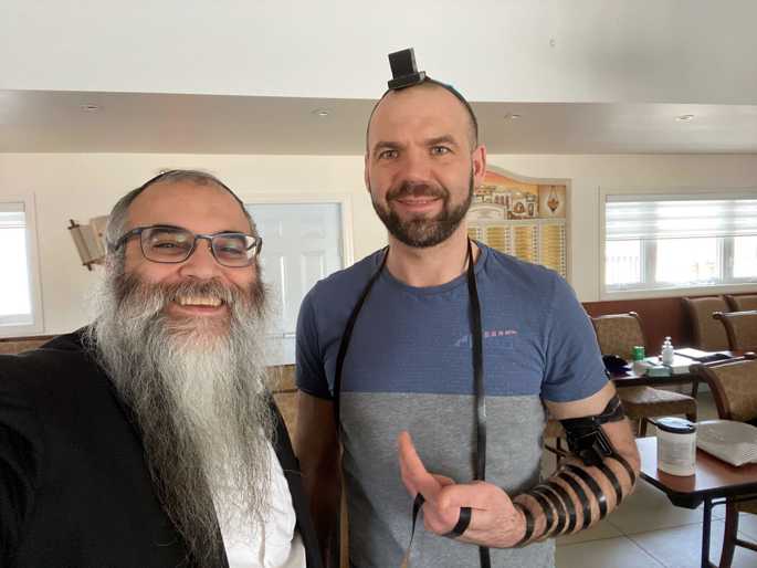 Rabbi Chaim Hildeshaim helps Victor Dotsenko put on tefillin. - Photo: Chabad Russian Center of Thornhill Woods