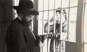 Rav Sholom Ber Lipskar, directeur du Aleph Institute, aide un détenu à mettre les Téfiline