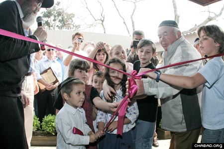 Curitiba, Brazil’s past meets its future as Holocaust survivor Naftali Steinberg joins a group of children in the ceremonial ribbon-cutting of the new Chabad-Lubavitch building. Rabbi Yoseph Dubrawsky, left, co-director of Chabad of Curitiba, looks on.