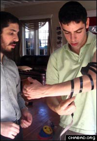Rabbi Elie Estrin helps a student at the University of Washington put on tefillin.