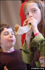 Brother and sister try their luck at blowing the shofar that they made in Helsinki, Finland.