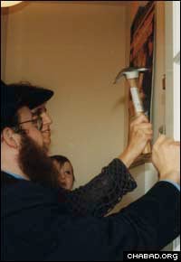 Rabbi Yossi Deren , a grandson of Risya Posner and co-director of Chabad-Lubavitch of Greenwich, Conn., assists in affixing a mezuzah on a Greenwich doorpost.