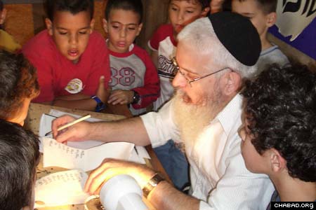 Children gather around a scribe as he demonstrates how one writes letters in a Torah scroll. (Photos: Meir Dahan)
