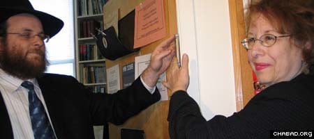 Rabbi Yonah Blum assists Columbia University professor Elizabeth Midlarsky affix a mezuzah to the doorway of her office, which last week was defaced with a swastika.