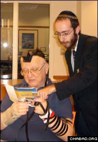 Rabbi Chesky Tenenbaum puts on tefillin with Martin Hershkowitz, who told the rabbi about the chaplaincy opening.