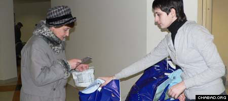 A volunteer hands out a filled package at Moscow’s Shaarei Tsedek Charity Center