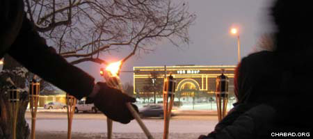 Rabbi Mendel Katzman, co-director of Chabad-Lubavitch of Nebraska, takes hold of a torch to light a Chanukah menorah across the street from the Van Maur department store at the Westroads Mall in Omaha on Dec. 6. The day before, a lone gunman opened fire on Van Maur shoppers, killing eight.