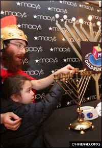 Judah the Maccabee teaches a child how to light the Chanukah menorah at a display at the Macy’s flagship department store on Manhattan’s 34th Street.
