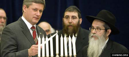 Canadian Prime Minister Stephen Harper, left, lights the Chanukah menorah’s shamash candle as senior Chabad-Lubavitch Rabbi Zalman Aharon Grossbaum looks on.