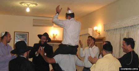 Chaim Harrari is lifted in a chair as Rabbi Arie Zeev Raskin, third from left, and others celebrate his Cypriot wedding.