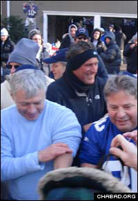 After putting tefillin on himself, New York Giants fan Jay Greenfield, right, assists others in donning the sacred items.