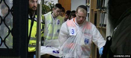 Workers with Israel’s ZAKA organization, which ensures proper burial of Jewish remains, remove one of the eight murdered students from Jerusalem’s Mercaz Harav yeshiva Thursday night.