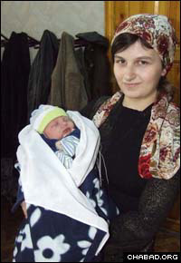 An alumnus of the STARS Jewish educational program in Tashkent, Uzbekistan, holds her newborn son soon after his ritual circumcision.