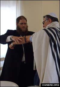Rabbi Chaim Hillel Azimov helps a Jewish resident of Northern Cyprus don tefillin.