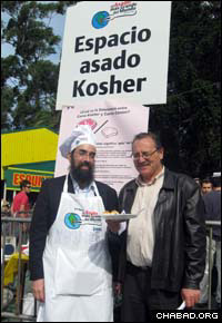 Rabbi Eliezer Shemtov, left, co-director of Chabad-Lubavitch of Uruguay, stands with Montevideo Mayor Ricardo Ehrlich at the kosher booth of the world’s largest barbeque.