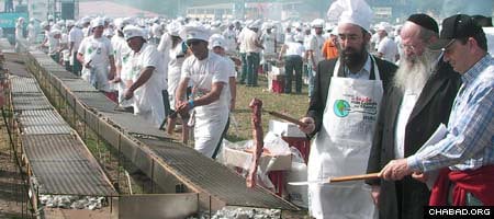 Chabad-Lubavitch Rabbi Eliezer Shemtov, third from right, grills a kosher steak to kick off a Montevideo, Uruguay barbeque that set the Guinness record for world’s largest.