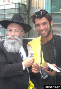 Rabbi Yaakov Gloiberman, left, helps a fan of the Maccabi Tel Aviv basketball team put on tefillin.