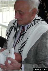 Liviu Librescu serves as the sandak for his grandson’s circumcision in Israel.
