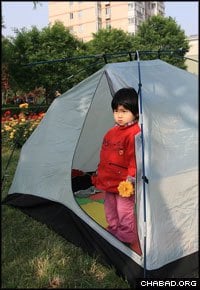 A little girl looks out from her tent in downtown Chengdu, China, after a powerful 7.9 magnitude earthquake prompted residents of the city’s towers to move to the streets outside. (Photo: Bruce Lee)