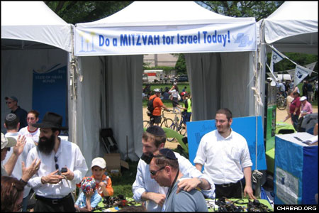 Rabbi Sholom Raichik, director of Chabad-Lubavitch of Upper Montgomery County in Maryland, coordinated the “Do a Mitzvah for Israel” booth at Sunday’s Israel @ 60 celebration held at the National Mall in Washington, D.C. More than 1,000 people stopped by to don tefillin, pick up Shabbat candles, or drop a coin in the charity box. American Friends of Lubavitch helped arrange the presence at the Jewish Federation of Greater Washington event.