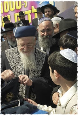 Le Rav Eliyahou à une cérémonie organisée par Colel ‘Habad lors de laquelle il donna à 500 garçons bar-mitsva une paire de Téfiline, parlant ici avec l’un des bar-mitsvas de l’importance de cette mitsva