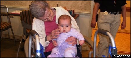 A resident of the Atria Woodlands senior living center in Ardsley, N.Y., holds a baby from the Mommy and Me group sponsored by Chabad-Lubavitch of the River Towns in Dobbs Ferry.