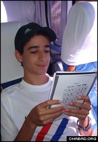 A teenage boy practices his prayers during a bus trip.