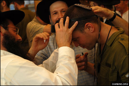 The idea for the bar mitzvah came to Ron, right, when a young Chabad-Lubavitch rabbinical student visited his base. The student, who regularly helped soldiers put on tefillin, learned that Ron had never before donned the prayer boxes worn by Jewish men the world over, and half-jokingly suggested that the officer celebrate his bar mitzvah on the spot. Ron, however, wanted a big party.