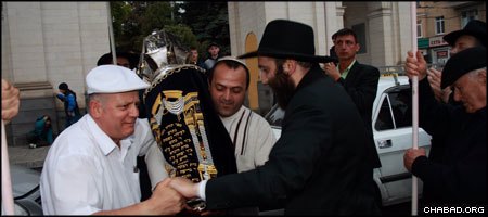 Local resident Hillel Davidov holds the first Torah scroll to be dedicated in Stavropol, Russia, in close to a century, while Rabbi Zvi Herschovich and another community members dance around him.