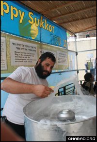 Natanel Malka makes cotton candy for passers-by at Chabad-Lubavitch of the Cardo’s sukkah.