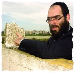 Raskin points out the hebrew inscription on a fragment of a tombstone